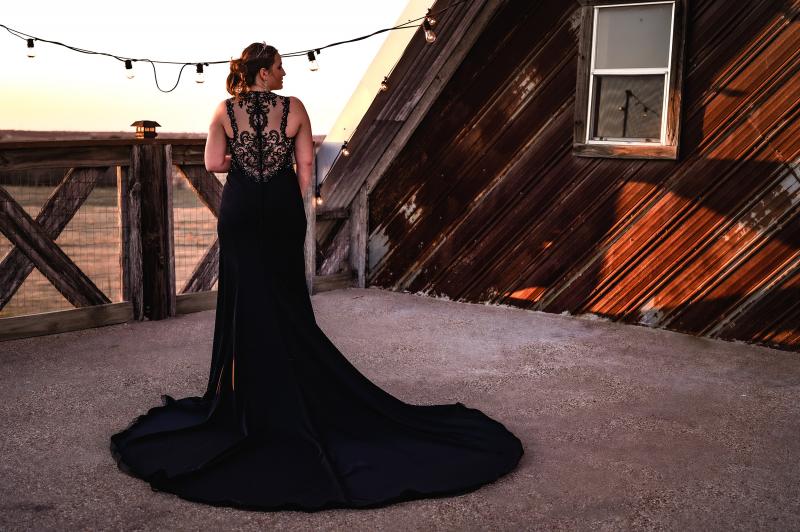 woman posing in a formal dress outside a rustic barn 